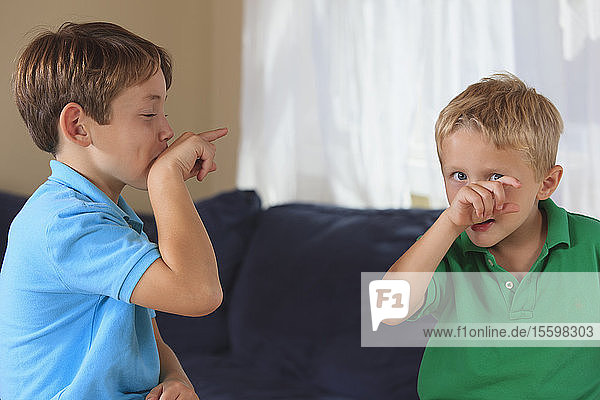 Boys with hearing impairments signing 'bird' in American sign language on their couch