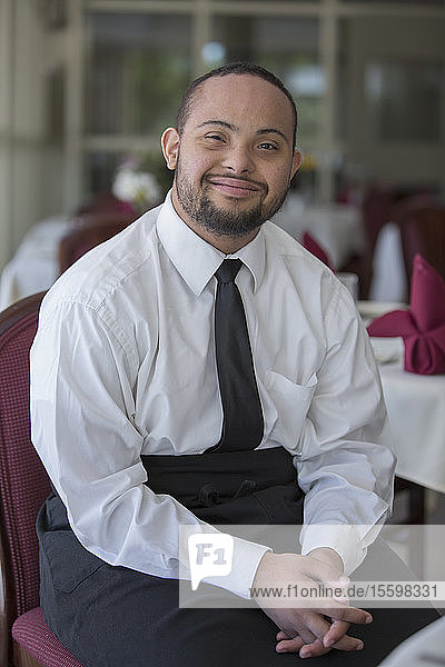 Portrait of happy African American man with Down Syndrome as a waiter in restaurant