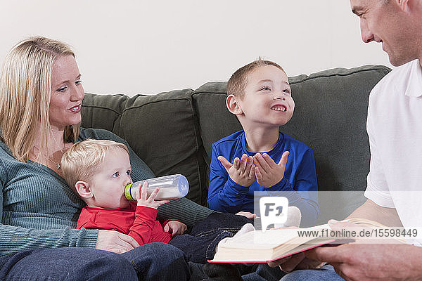 Junge  der das Wort Book in amerikanischer Zeichensprache gebärdet  während er mit seinen Eltern lernt