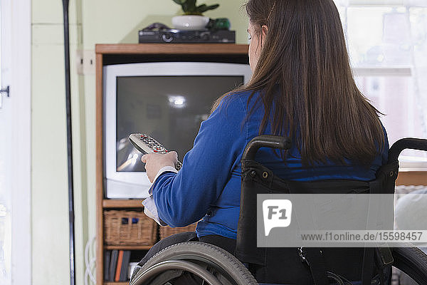 Frau mit Spina Bifida in einem Rollstuhl beim Fernsehen
