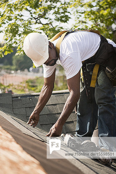 Zimmermann beim Ausrichten der Schindeln auf dem neuen Dach