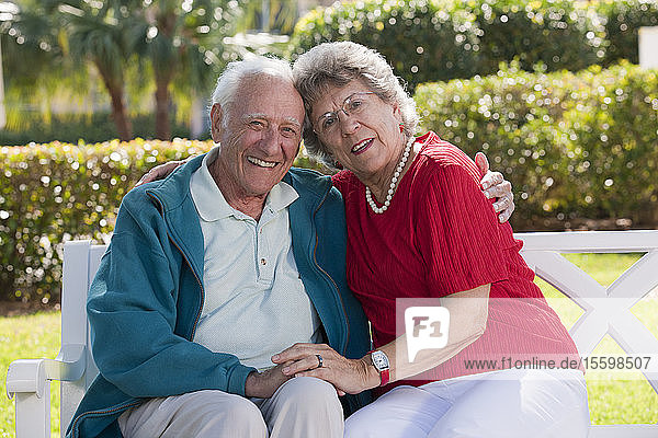 Älteres Paar mit Arm um sitzen auf einer Parkbank