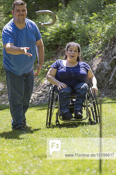 Frau mit Spina Bifida im Rollstuhl spielt Hufeisen mit ihrem Mann