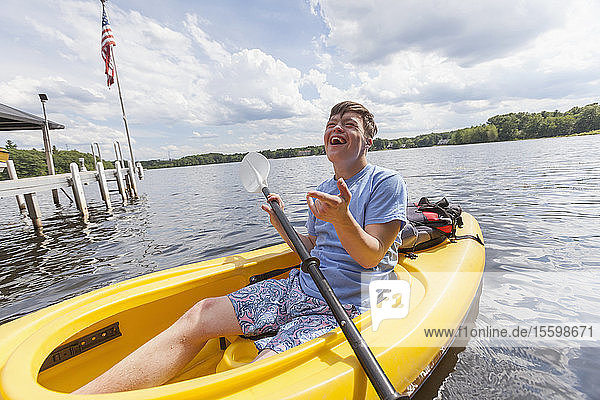 Glücklicher junger Mann mit Down-Syndrom rudert im Kajak auf einem See