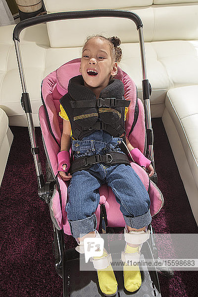 Kleines Mädchen mit Cerebralparese bereit für eine Fahrt im Kinderwagen