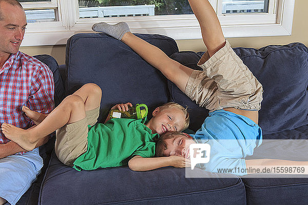 Vater und Söhne mit Hörbehinderung spielen auf der Couch