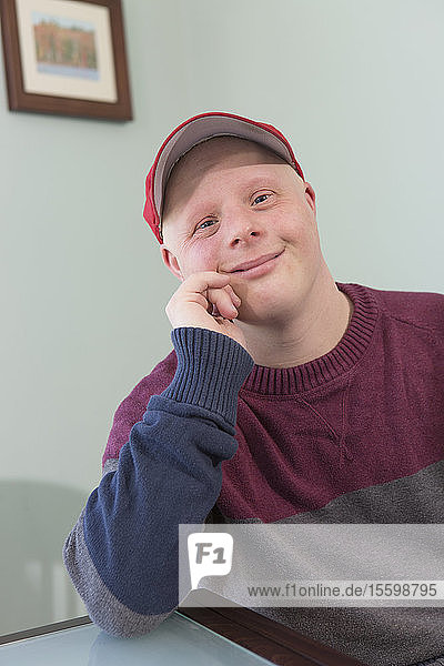 Porträt eines glücklichen jungen Mannes mit Down-Syndrom zu Hause