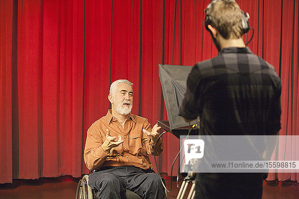 Ein Mann mit Muskeldystrophie und Diabetes spricht in einem Fernsehstudio in eine Kamera