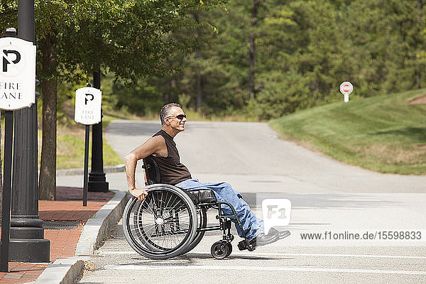 Man with spinal cord injury in a wheelchair crossing at accessible street walk