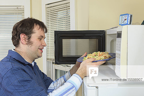 Mann mit Asperger-Syndrom lebt in seinem Haus und kocht in der Mikrowelle