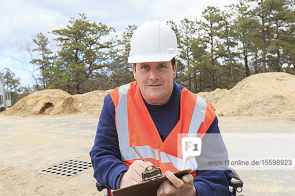 Construction engineer with spinal cord injury making notes at the site