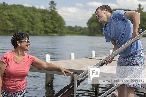 Junger Mann mit Down-Syndrom bereitet sich mit seinem Freund auf die Benutzung eines Bootes an einer Anlegestelle vor