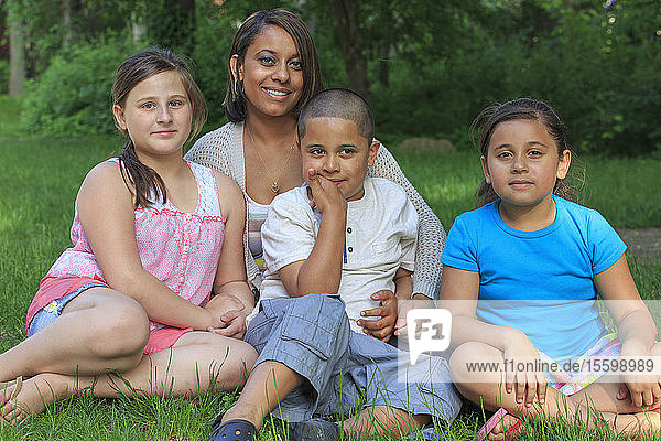 Hispanic family with Autistic boy sitting together in park
