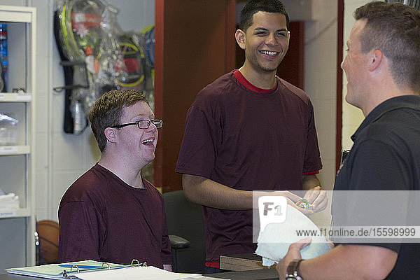 Young man with Down Syndrome having fun at college equipment dispensary with his friends