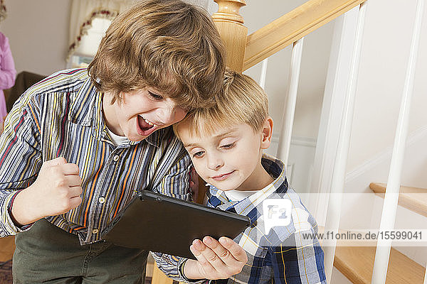 Close-up of two brothers playing on a digital tablet