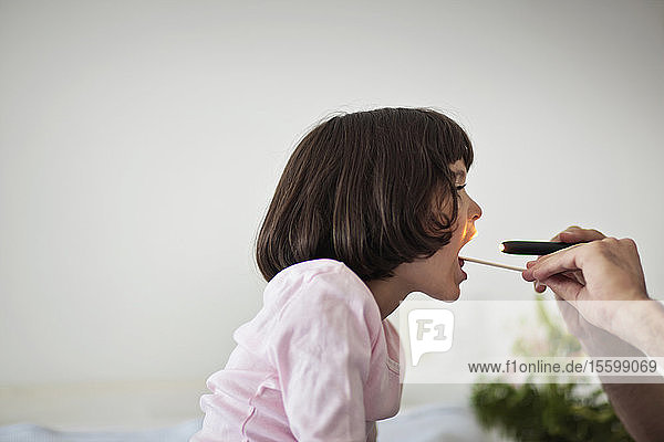 Junges Mädchen streckt die Zunge zur medizinischen Untersuchung heraus