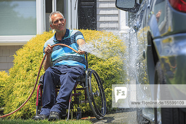 Man with a Spinal Cord Injury in wheelchair washing his accessible car