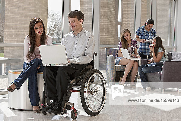 Lehrerin mit Rückenmarksverletzung und Schüler arbeiten an einem Laptop