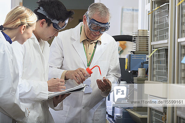 Professor bei der Arbeit mit Ingenieurstudenten  die in einem Labor Ethanol in eine Probenschale geben