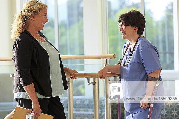 Zwei Krankenschwestern in einer Klinik  eine mit Cerebralparese an Stöcken