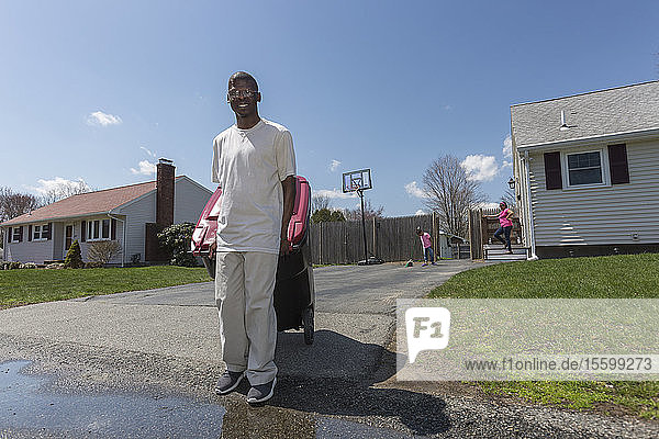 Mann mit Williams-Syndrom bringt den Müll raus  mit seiner Familie im Hintergrund