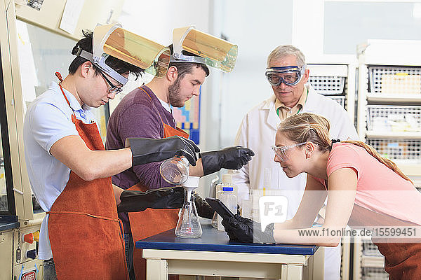 Ingenieurstudenten und Professor tragen Schutzausrüstung bei der Arbeit im Chemielabor