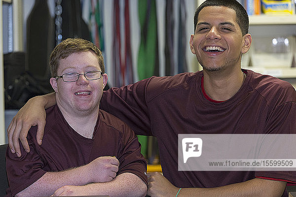 Junger Mann mit Down-Syndrom amüsiert sich mit dem Betreuer in der Ausgabestelle für Hochschulausrüstung