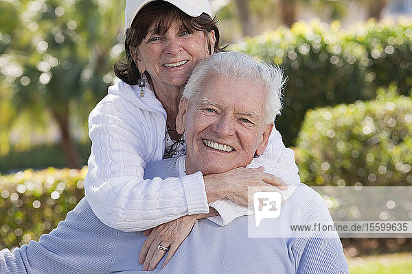 Portrait of a senior woman hugging a senior man from behind