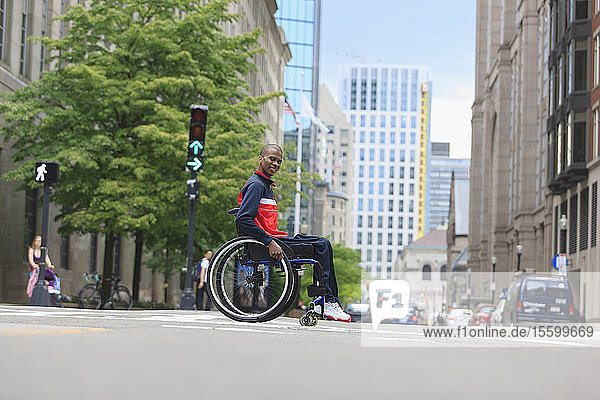 Man in wheelchair who had Spinal Meningitis crossing a city street