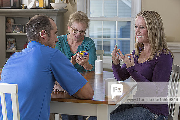 Drei Personen bei einem Treffen und zwei  die sich in ASL über Familie zu Hause unterhalten