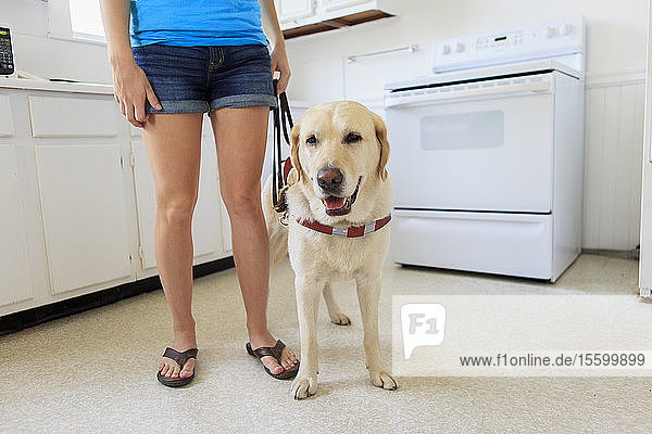 Frau mit Sehbehinderung in der Küche mit ihrem Diensthund
