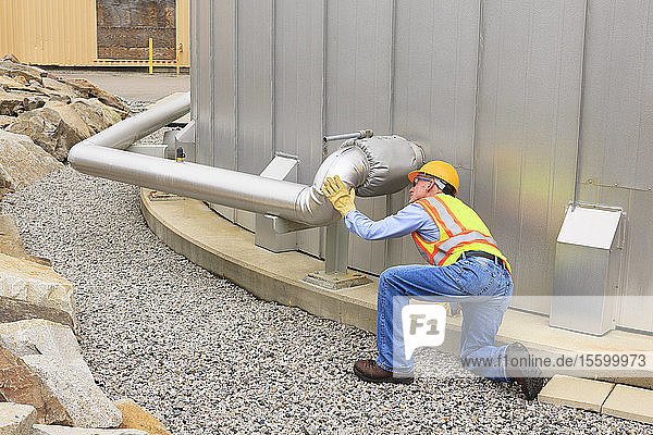 Engineer examining pipeline of water storage tank at electric power plant