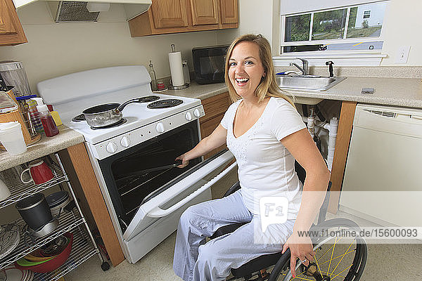 Woman with spinal cord injury in her accessible kitchen using a stove