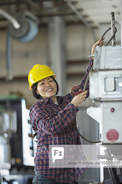 Female power engineer securing cable to equipment truck