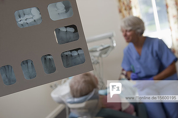 Nahaufnahme eines zahnärztlichen Röntgenberichts mit Zahnärztin und Patientin