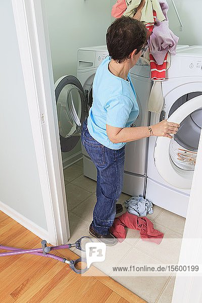 Woman with cerebral palsy washing clothes in the laundry room