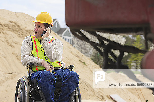 Construction supervisor with Spinal Cord Injury on walkie talkie on construction site