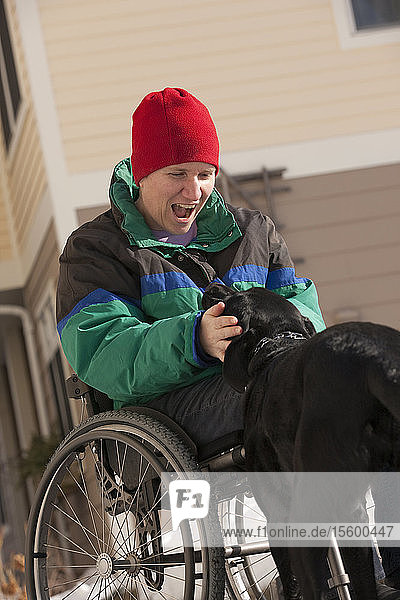 Frau mit Multipler Sklerose spielt mit einem Diensthund