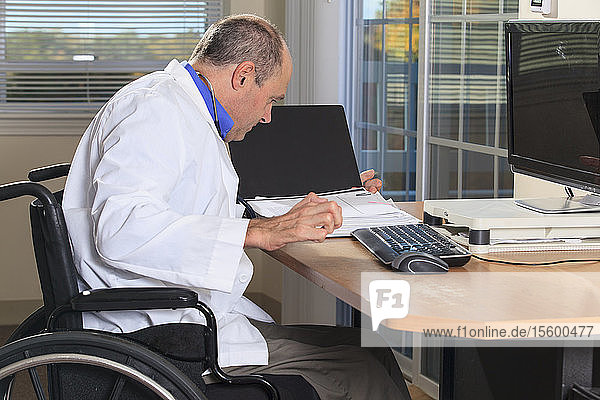 Man with Friedreich's Ataxia and deformed hands as a doctor looking at patient records at his computer