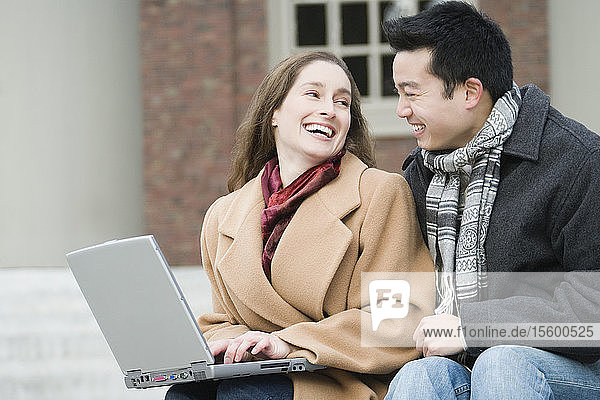 Nahaufnahme einer jungen Frau  die einen Laptop benutzt und mit ihrer Freundin lächelt
