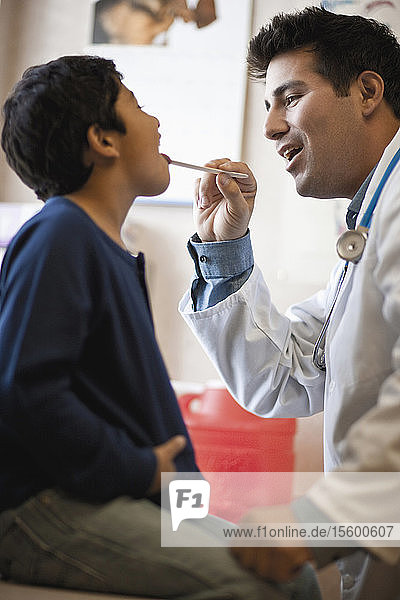 Arzt untersucht den Rachen eines Jungen mit einem Zungenspatel