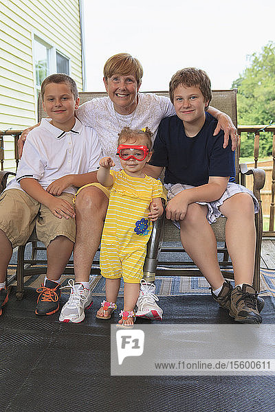 Großmutter mit Beinprothese mit ihren Enkelkindern auf ihrer Terrasse sitzend