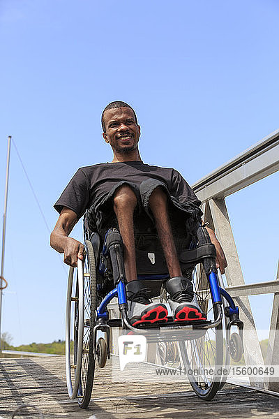 Man in a wheelchair who had Spinal Meningitis going down a ramp to a dock