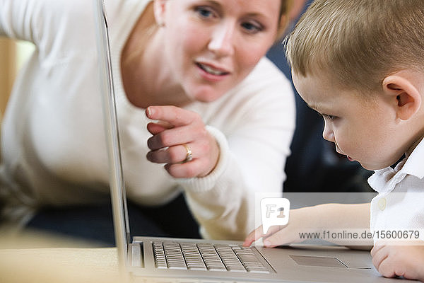 Blick auf eine Mutter  die ihrem Sohn den Umgang mit dem Computer beibringt.