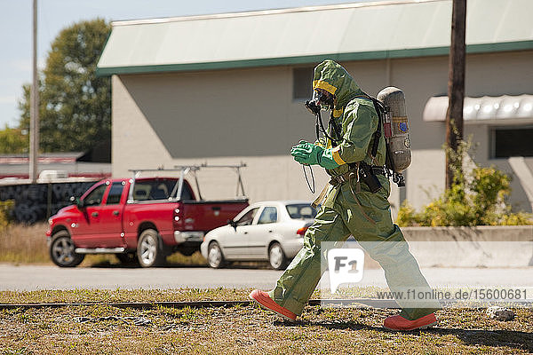 HazMat firefighter walking in a field with a camera