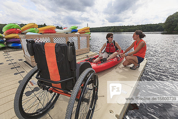 Instructor helping a woman with a Spinal Cord Injury with using a kayak