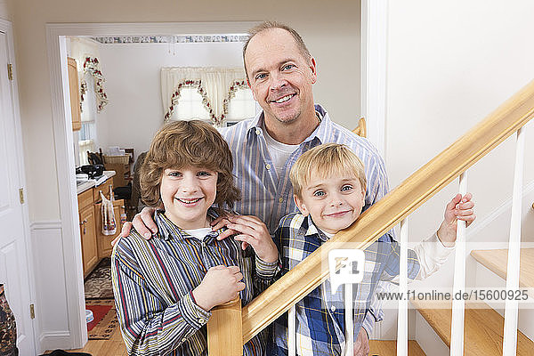 Porträt eines glücklichen Mannes mit seinen beiden Söhnen zu Hause