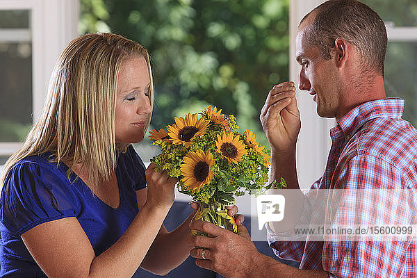 Husband giving flowers to his wife and signing 'Flower' in American sign language both with hearing impairments