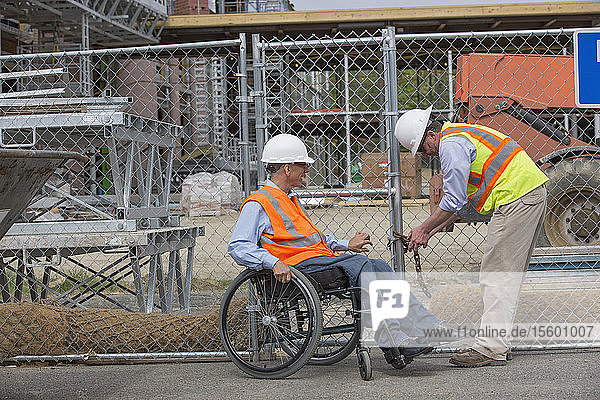 Zwei Projektingenieure nähern sich der Baustelle  einer sitzt im Rollstuhl und hat eine Rückenmarksverletzung
