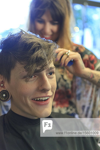 Stilvoller Mann mit einer Rückenmarksverletzung lässt sich in einem Friseursalon die Haare schneiden